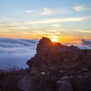 A breathtaking sunset over clouds atop the Haleakala during Maui hiking.