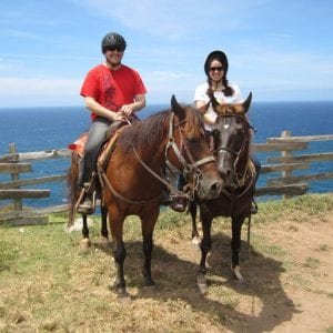 Two people on horses enjoying a scenic ride along the ocean in Maui.