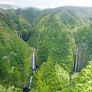 A vibrant green valley with waterfalls during the Maverick helicopter tour in Maui.